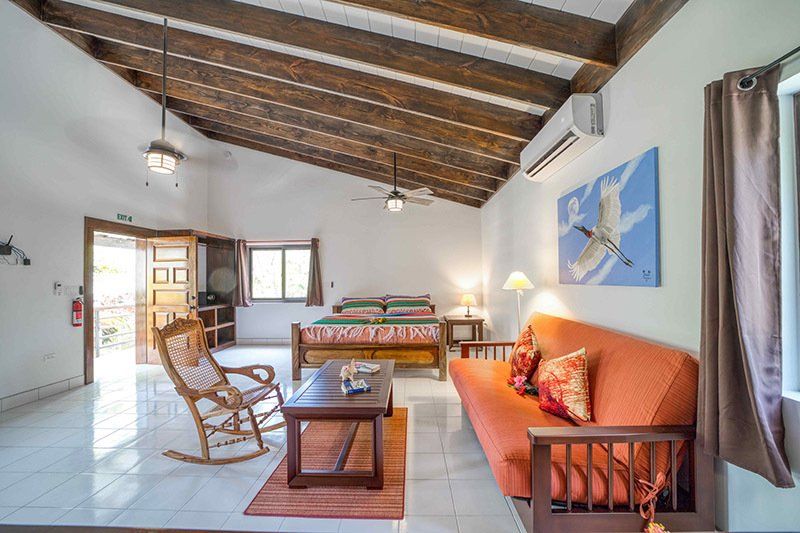 A living room with a couch , rocking chair , coffee table and bed.