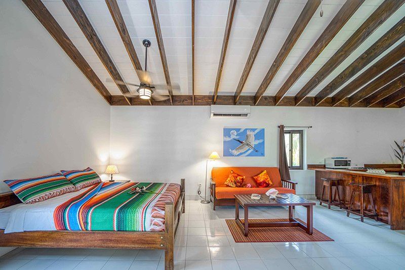 A bedroom with a bed , couch , table and ceiling fan.