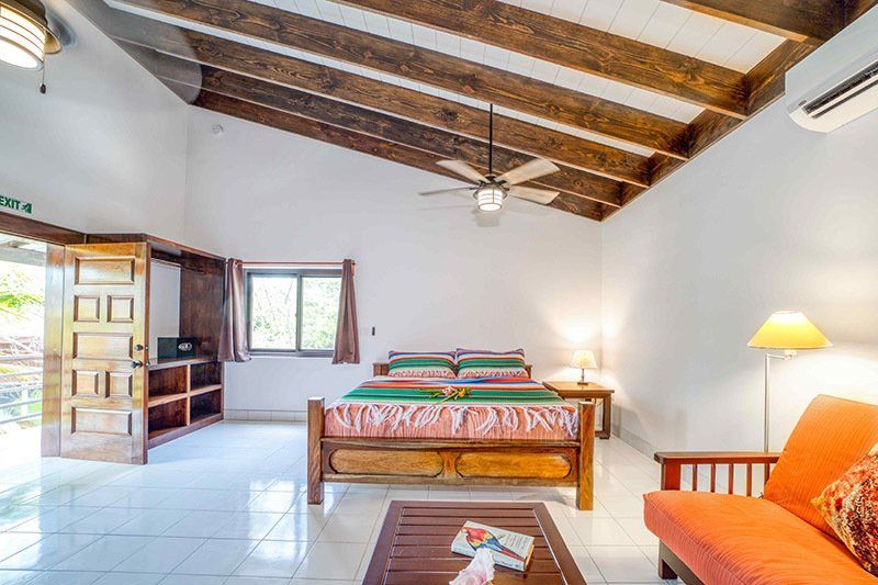 A bedroom with a bed , couch , coffee table and ceiling fan.