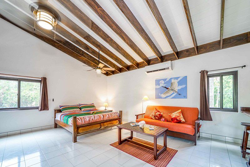 A bedroom with a bed , couch , coffee table and ceiling fan.