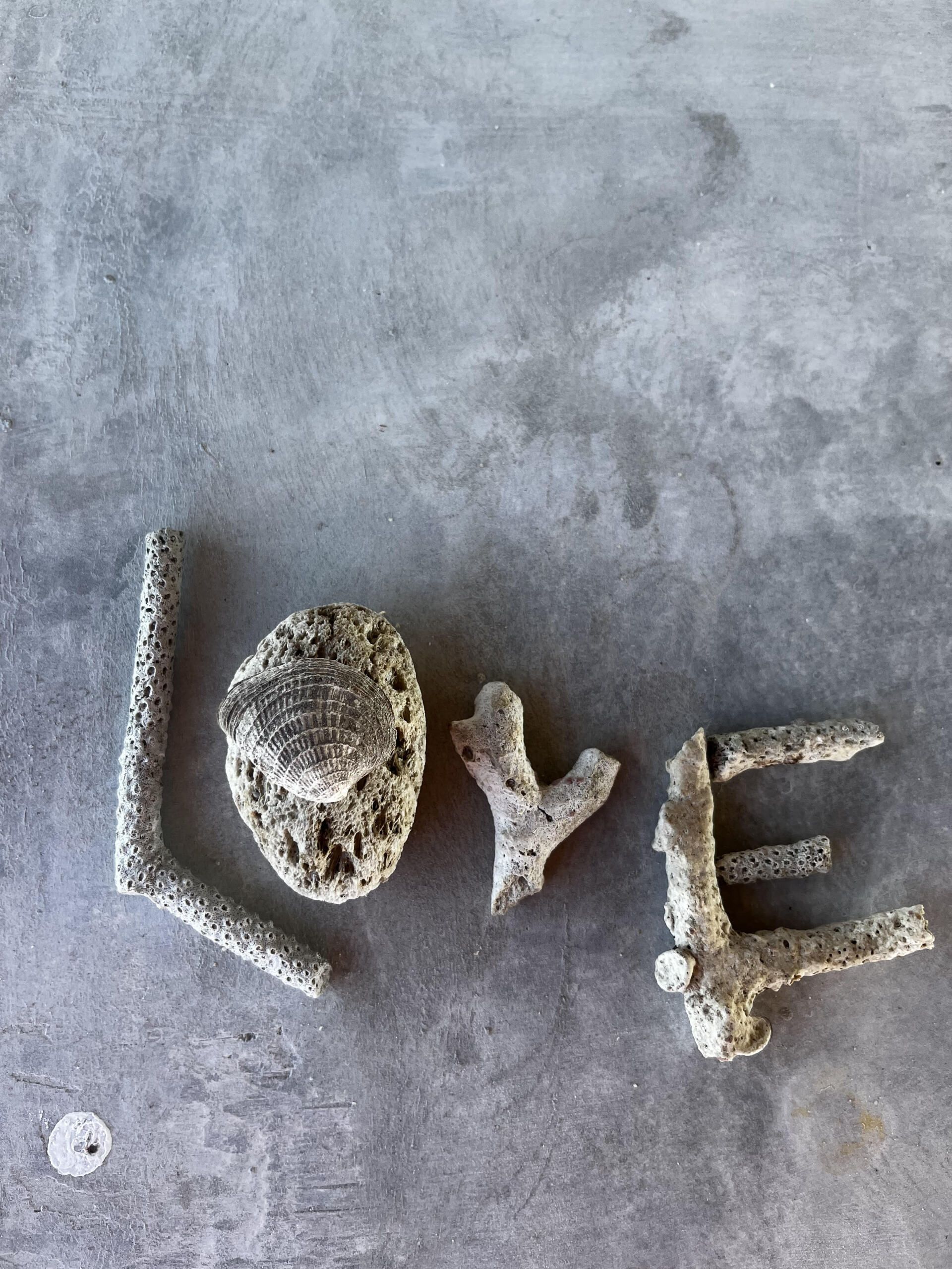 The word love is written in rocks on a concrete surface.