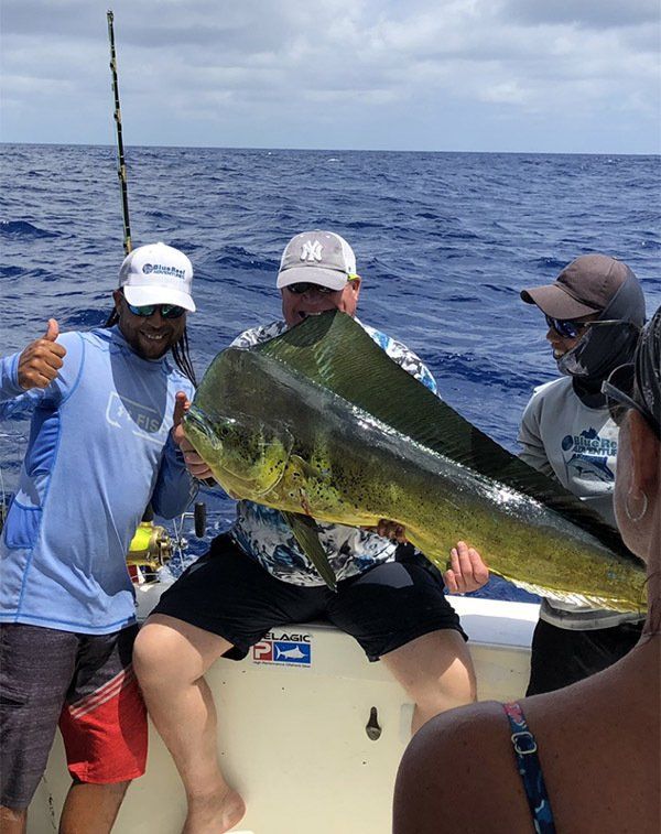 A man is holding a large fish on a boat in the ocean.