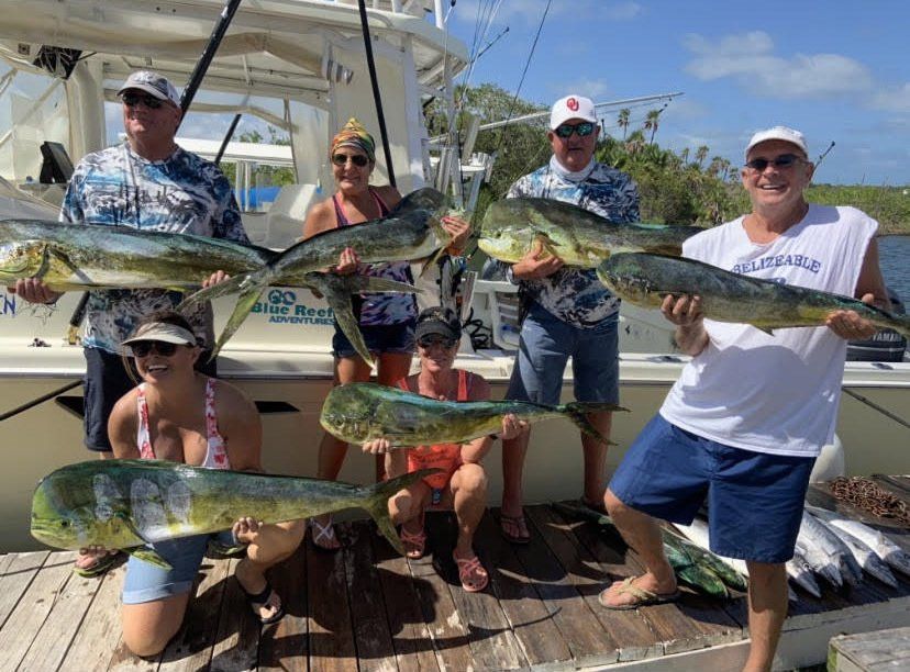A group of people are standing on a boat holding fish.