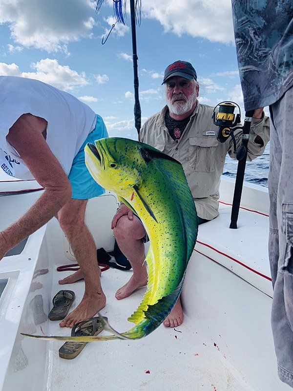Two men are sitting on a boat holding a large fish.