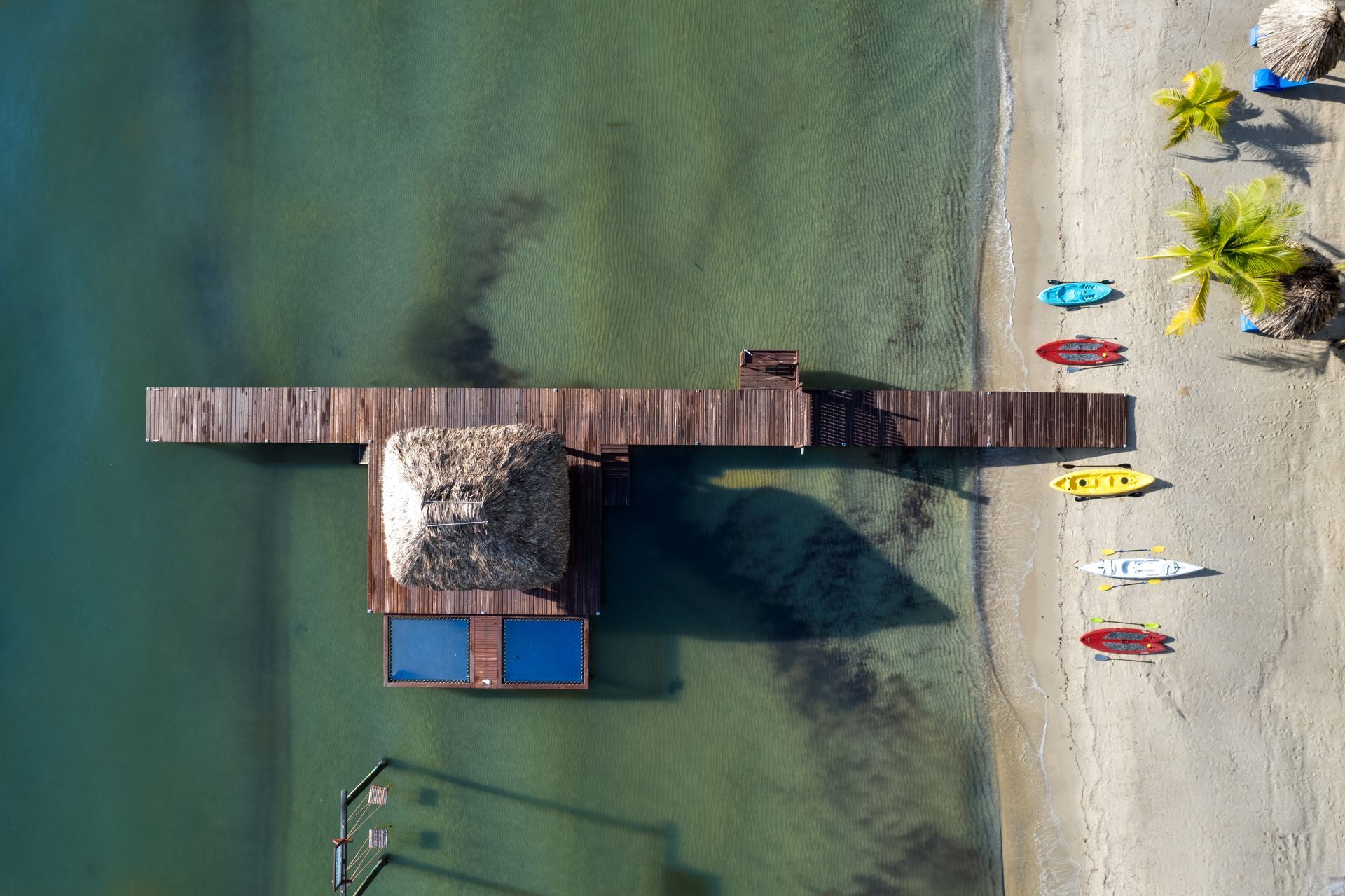 An aerial view of a dock and kayaks on a beach.