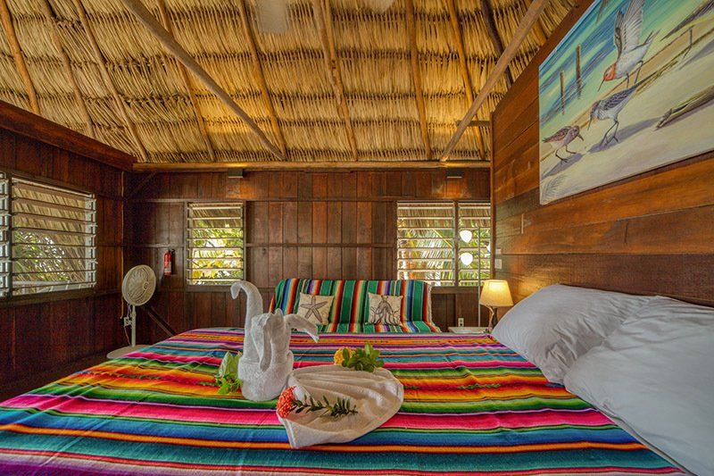 There is a bed with a colorful blanket and a couch in the room.