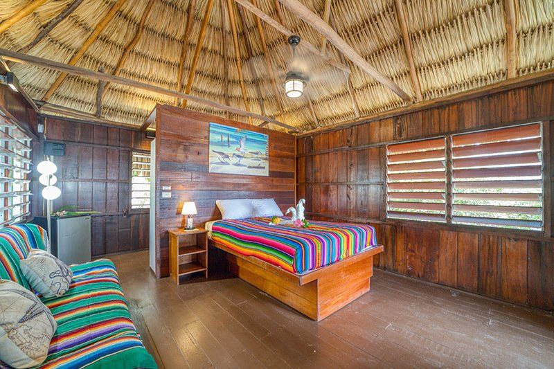 A bedroom in a hut with a couch and a bed.
