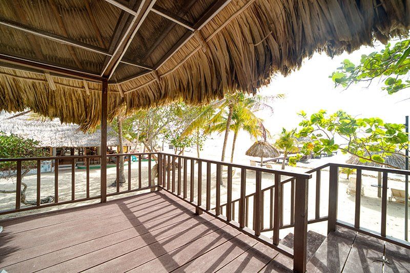 A balcony with a thatched roof overlooking the ocean