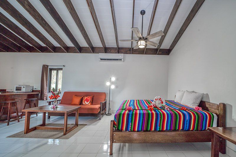 A bedroom with a bed , couch , coffee table and ceiling fan.