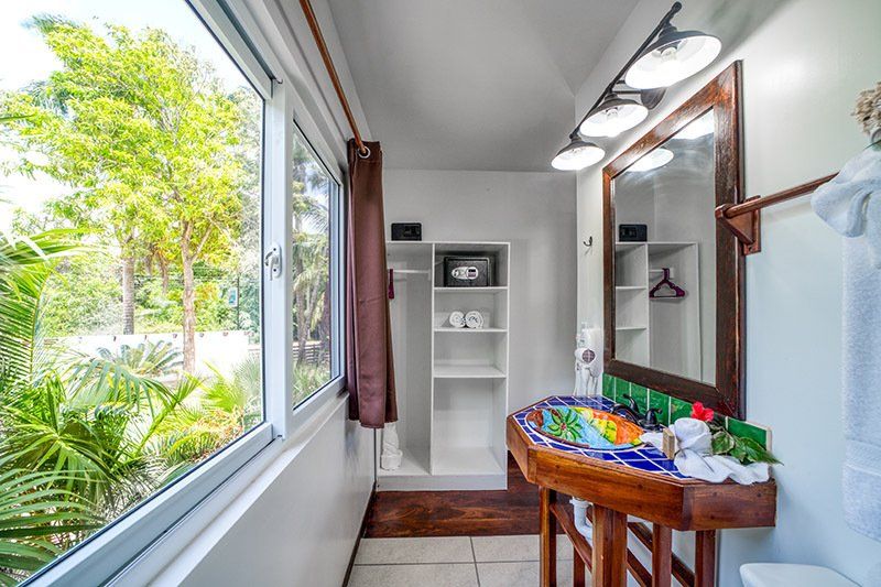 A bathroom with a sink , toilet , mirror and window.