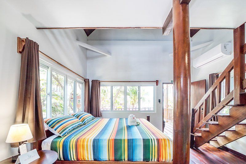 A bedroom with a striped bed and stairs leading up to the second floor.