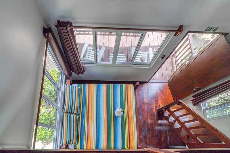 An aerial view of a bedroom with a striped bed and stairs.