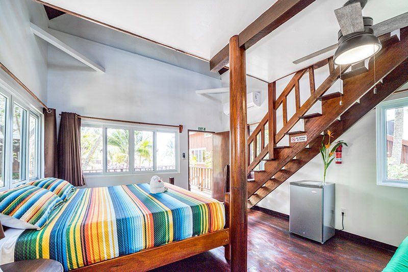 A bedroom with a king size bed and stairs leading up to the second floor.