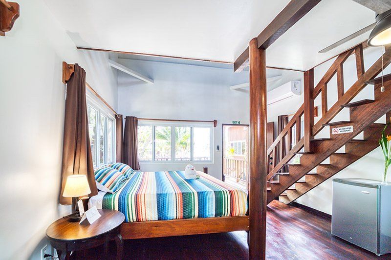 A bedroom with a bed and stairs leading up to the second floor.