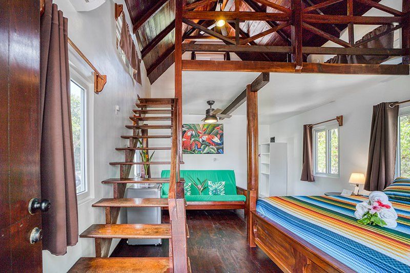 A bedroom with a bed , couch , and stairs leading to the second floor.