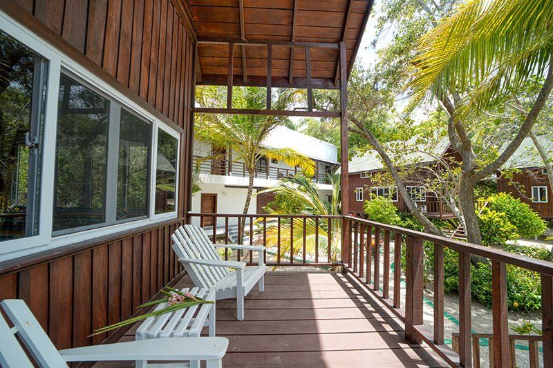A wooden deck with chairs and a bench in front of a house.