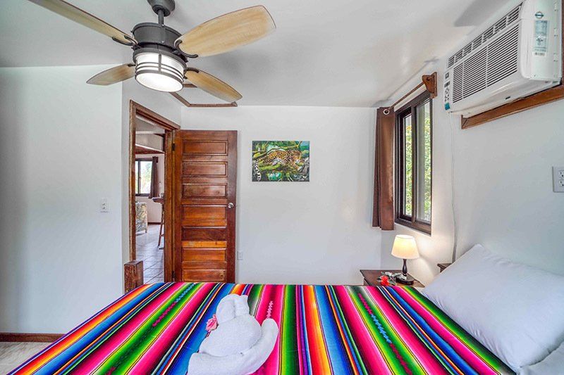 A bedroom with a colorful blanket and a ceiling fan.