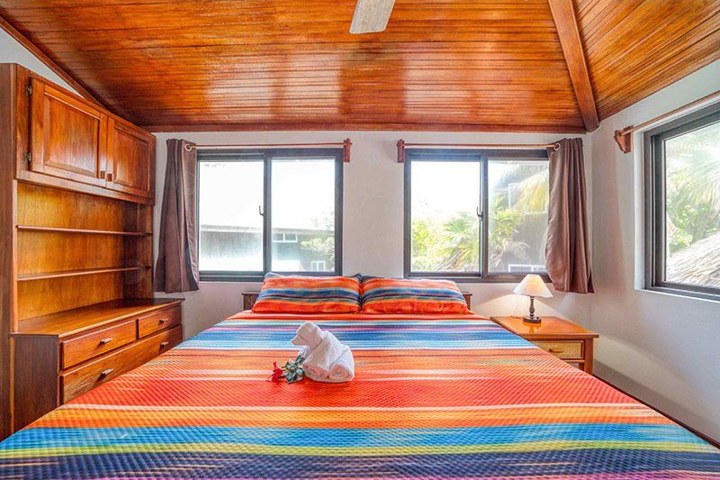 A bedroom with a king size bed , two nightstands , a dresser and a ceiling fan.