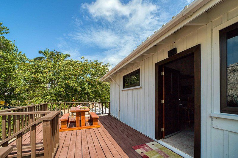 A white house with a wooden deck and a picnic table on it.
