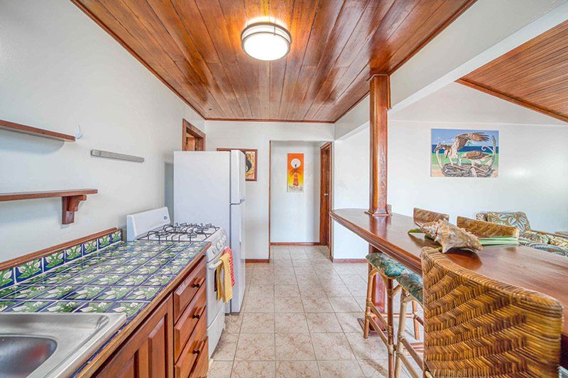 A kitchen with a refrigerator , stove , sink and stools.