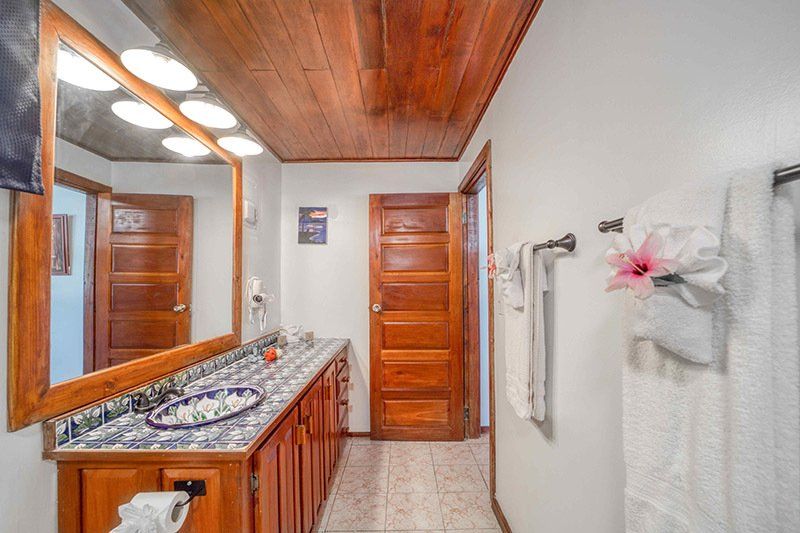 A bathroom with a sink , mirror , and towels hanging on the wall.