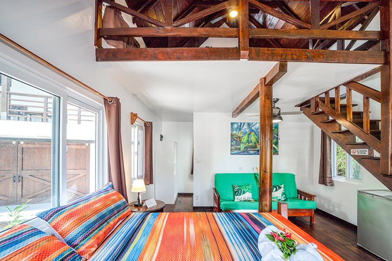 A bedroom with a bed , couch , and stairs in a house.