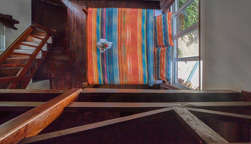 A wooden staircase leading up to a room with a colorful rug on the floor.