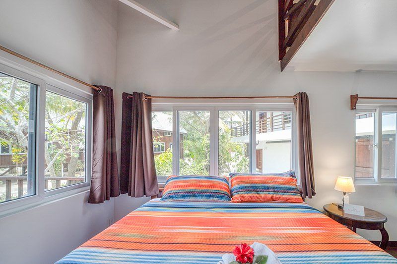 There is a bed in the middle of the room with a lot of windows.