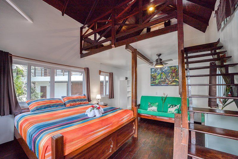 A bedroom with a king size bed and a green couch.