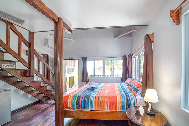 A bedroom with a king size bed and stairs leading up to the second floor.