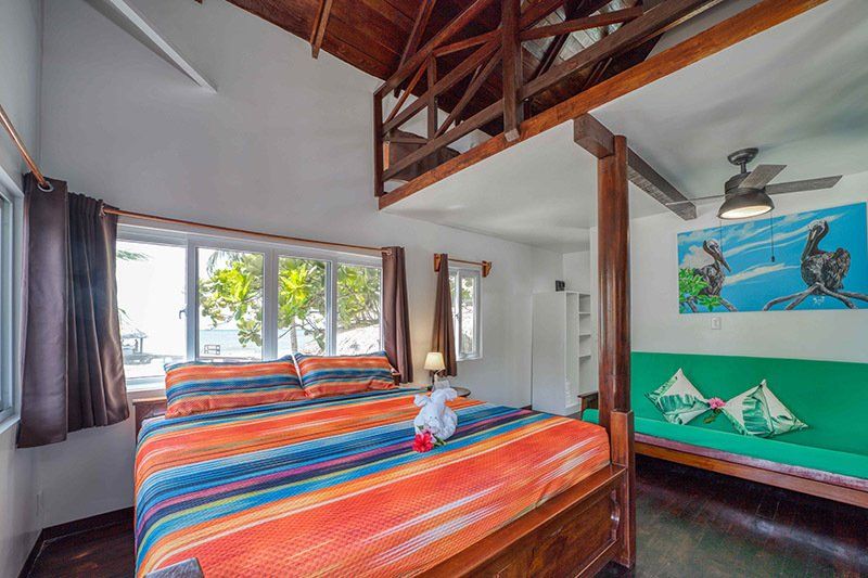 A bedroom with a king size bed and a green couch.