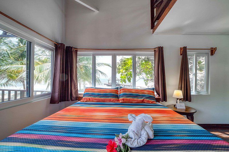 There is a bed in the middle of the room with a view of the ocean.