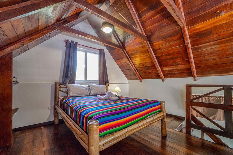 There is a bed in the attic with a wooden ceiling.