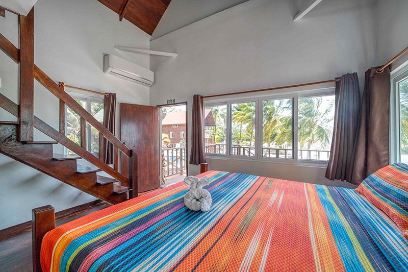 A bedroom with a king size bed and stairs leading up to the second floor.