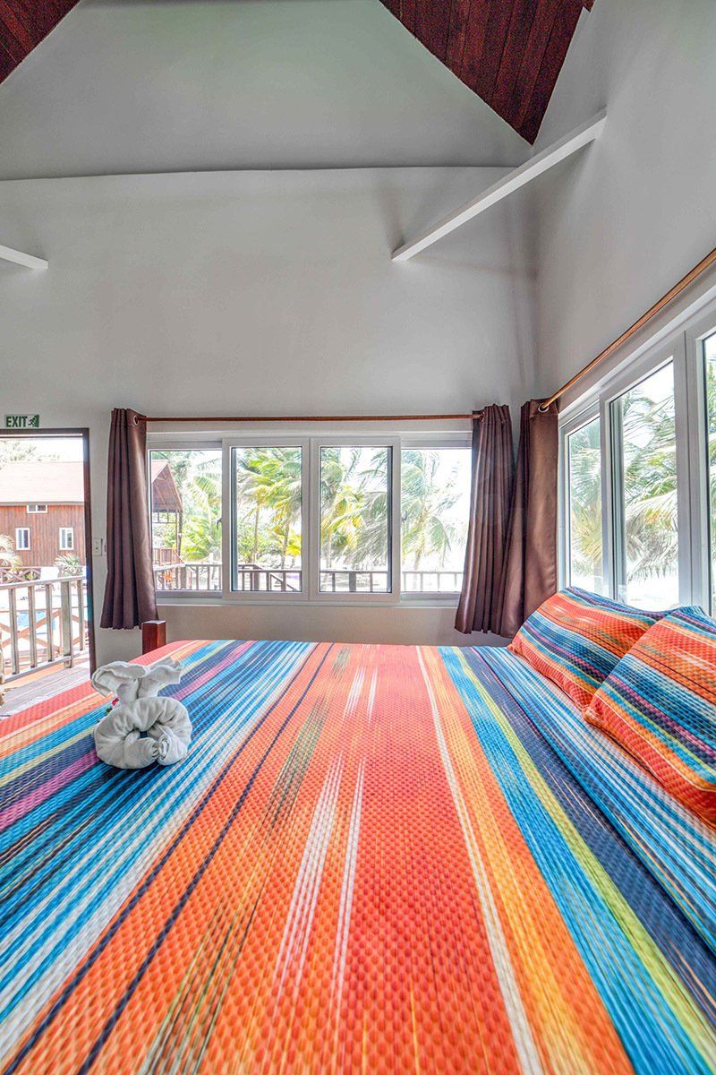 A bedroom with a colorful bed and lots of windows.