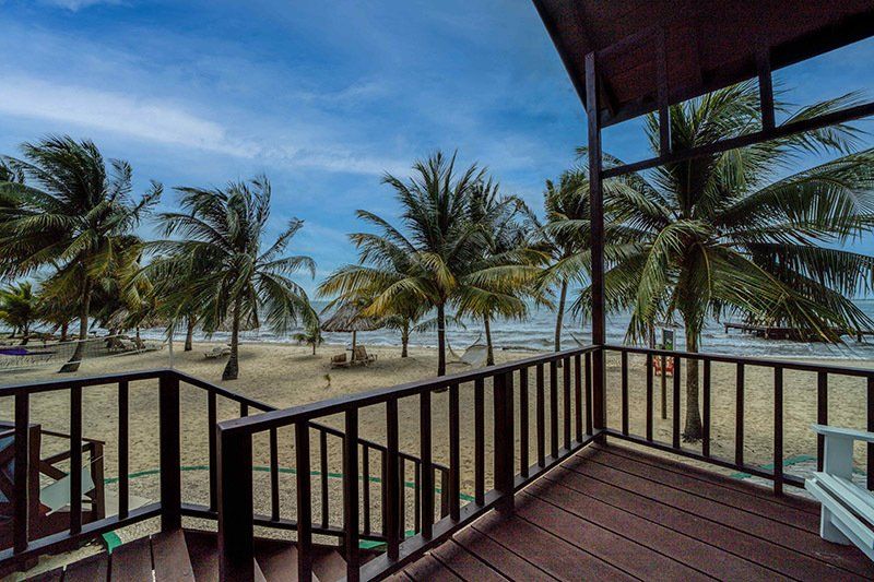 There is a balcony with a view of the beach and palm trees.