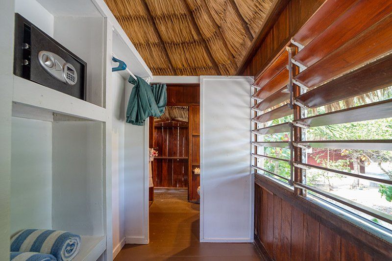 A walk in closet with a safe in the corner and a thatched roof.