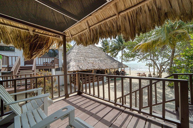 A balcony with chairs and a table overlooking the beach.