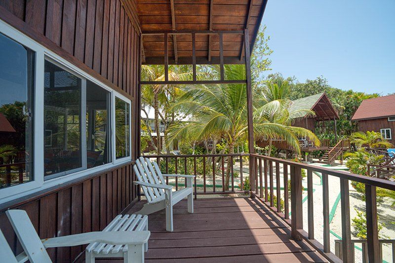 There are two chairs on the balcony of a wooden house.