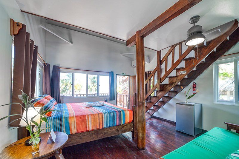 A bedroom with a king size bed and stairs leading up to the second floor.