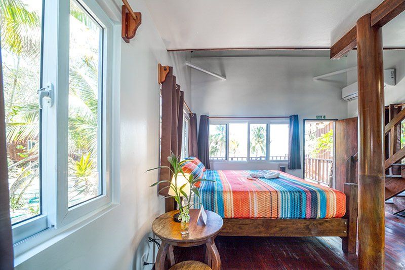 A bedroom with a bed , table , window and stairs.
