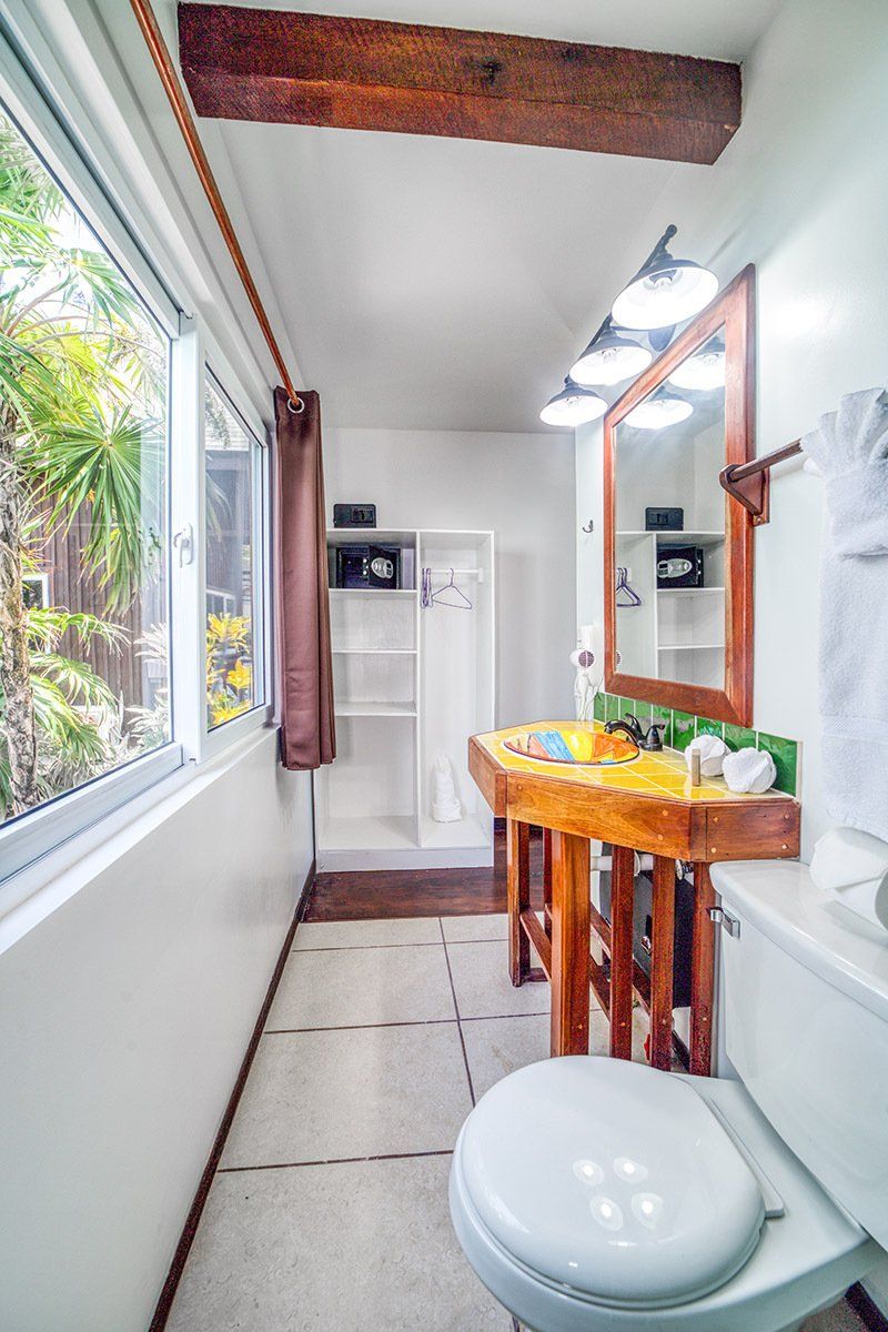 A bathroom with a toilet , sink , mirror and window.