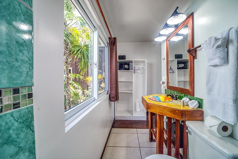 A bathroom with a sink , toilet , mirror and window.