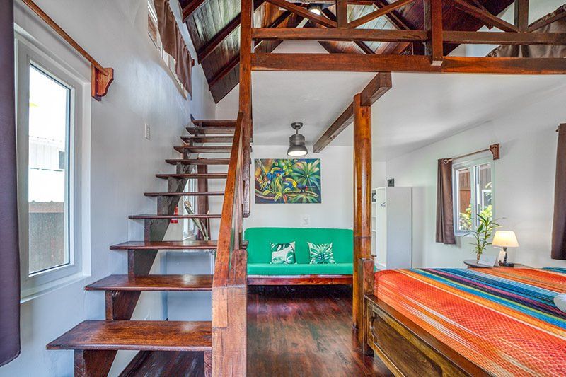 A bedroom with a green couch and stairs leading up to the second floor.