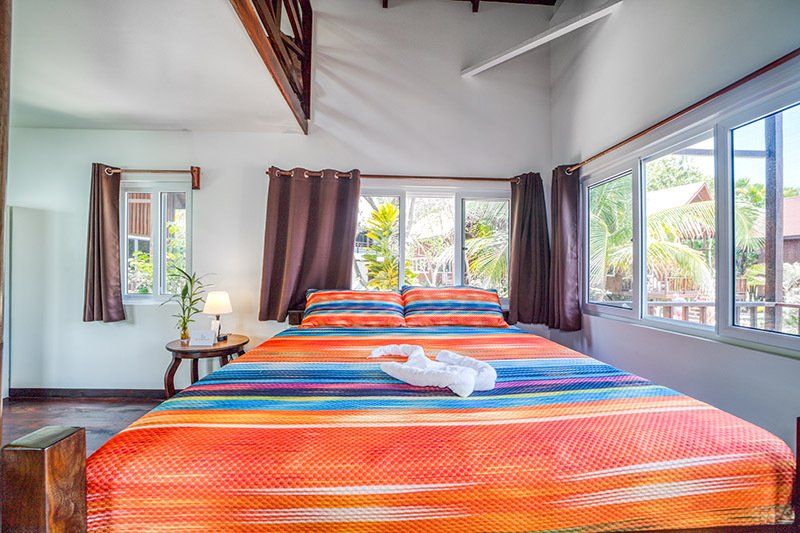 A bedroom with a large bed and lots of windows.