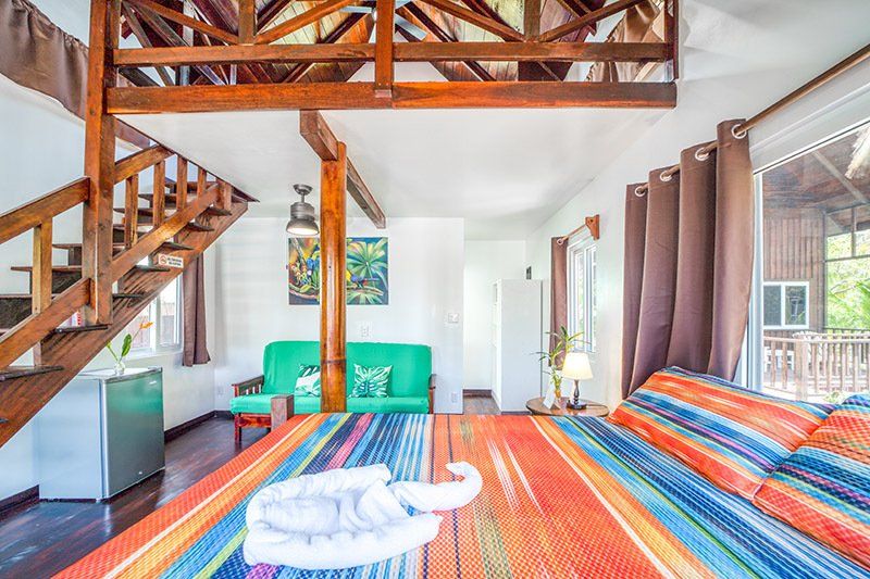 A bedroom with a bed , couch , and stairs.