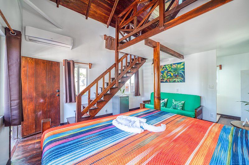 A bedroom with a king size bed , stairs and a green couch.