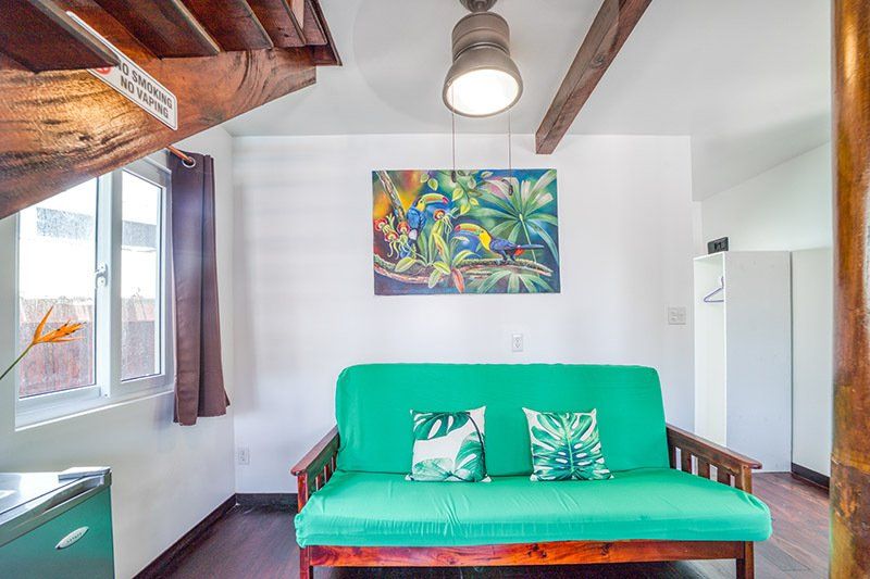 A living room with a green couch and a painting on the wall.