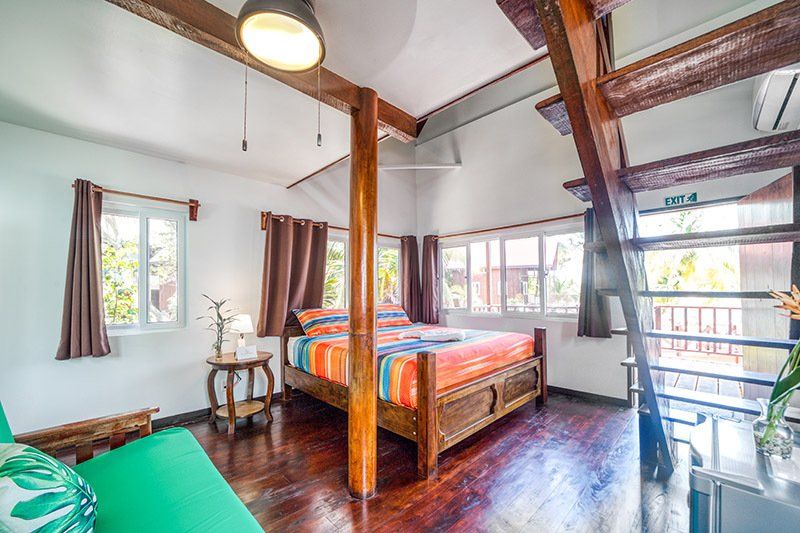 A bedroom with a bed , couch , and stairs.