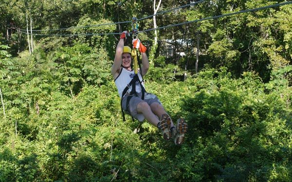 A woman is flying through the air on a zip line.